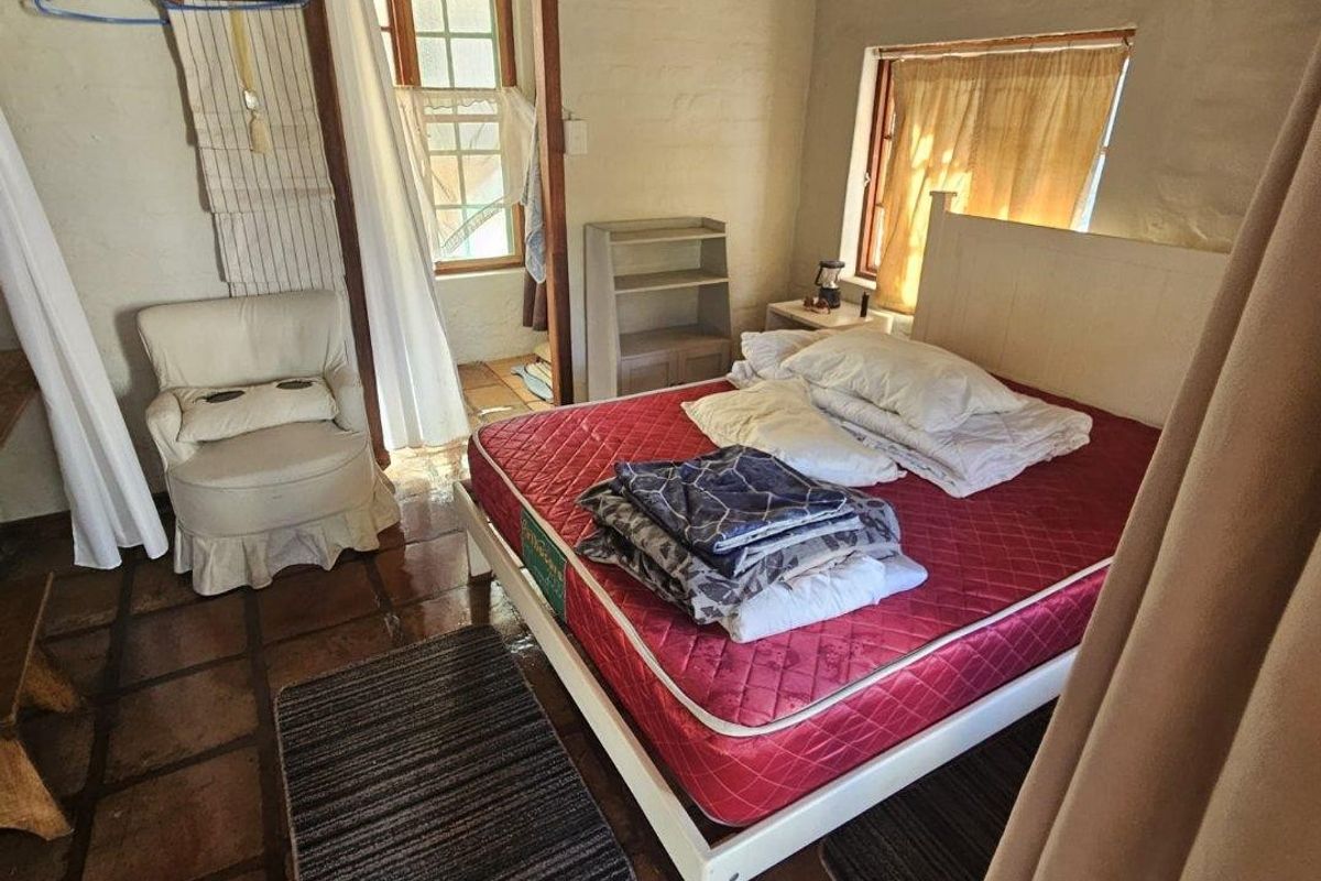 A rustic bedroom featuring traditional terracotta tile flooring and exposed masonry walls, offering a characterful space with direct access to an adjoining room.