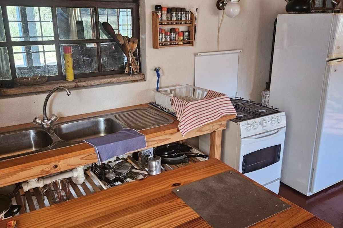 Rustic kitchen area featuring a wooden countertop, double stainless steel sink, and a gas stove, showcasing a charming farmhouse aesthetic.
