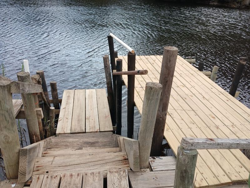 A wooden jetty and staircase providing access to the water, featuring newly installed timber decking and rustic support posts.