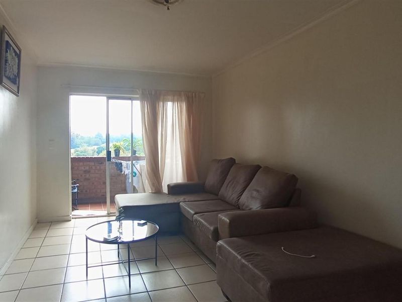 A living room featuring ceramic floor tiles and a sliding glass door providing access to an outdoor patio area.