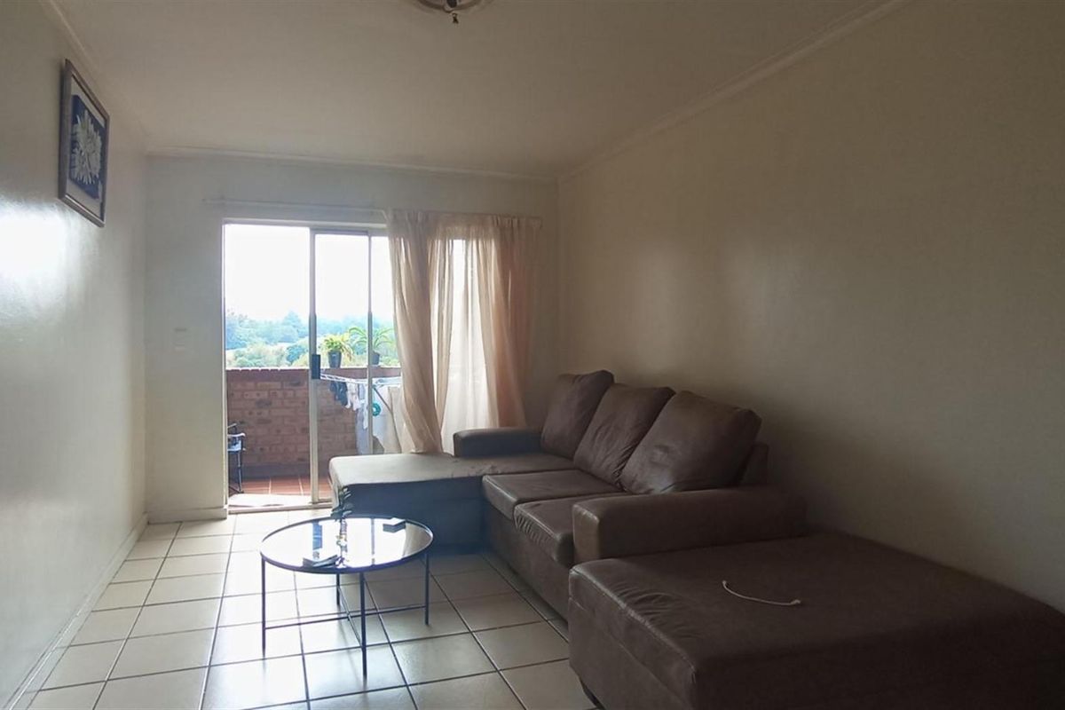 A living room featuring ceramic floor tiles and a sliding glass door providing access to an outdoor patio area.