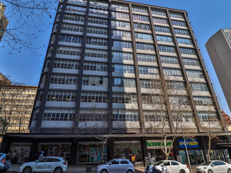 A multi-story commercial building featuring a grid-pattern facade with extensive glazing and ground-level retail storefronts in an urban setting.