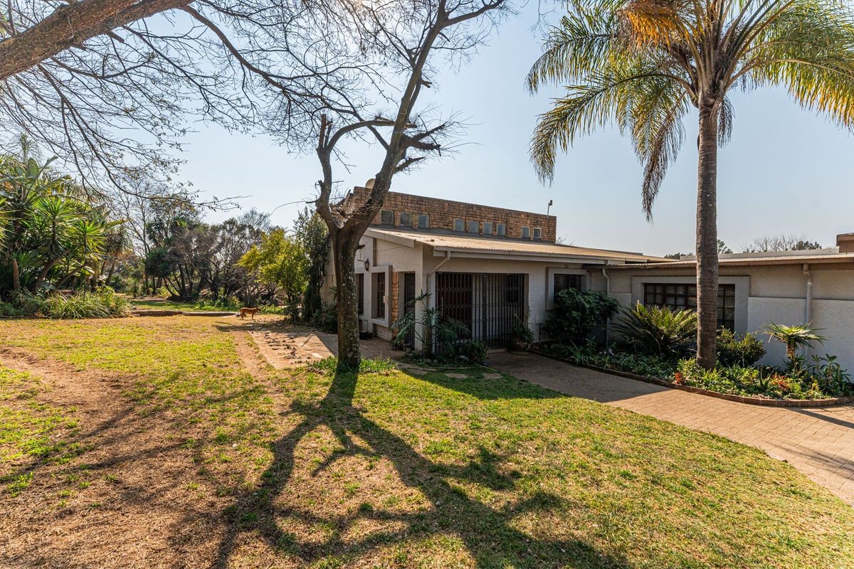 Rear view of the property featuring a paved walkway, established garden, and brick exterior detailing.