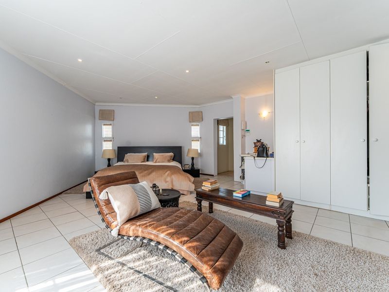 Spacious bedroom featuring neutral tiled flooring, recessed downlighting, and extensive built-in cupboard storage.