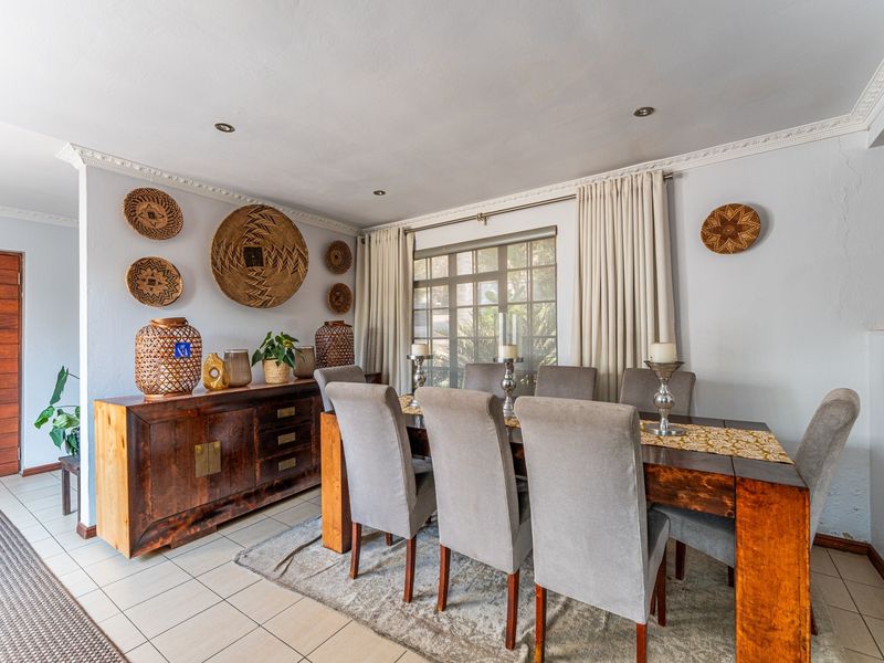A dining room featuring tiled flooring, decorative ceiling cornices, and a grid-pattern window, providing a functional space for family meals.