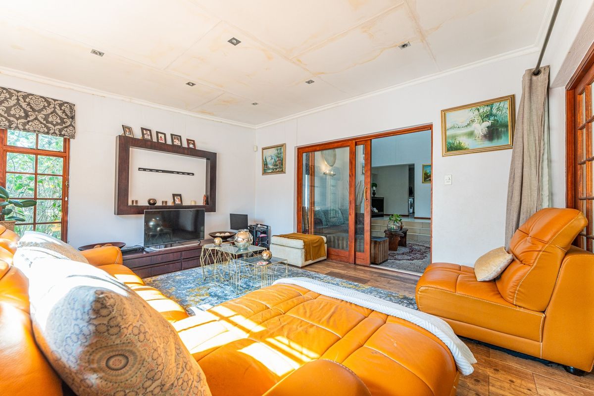 Spacious living room featuring laminate flooring, built-in shelving, and sliding glass doors leading to an adjacent room. Note visible water damage on the ceiling.
