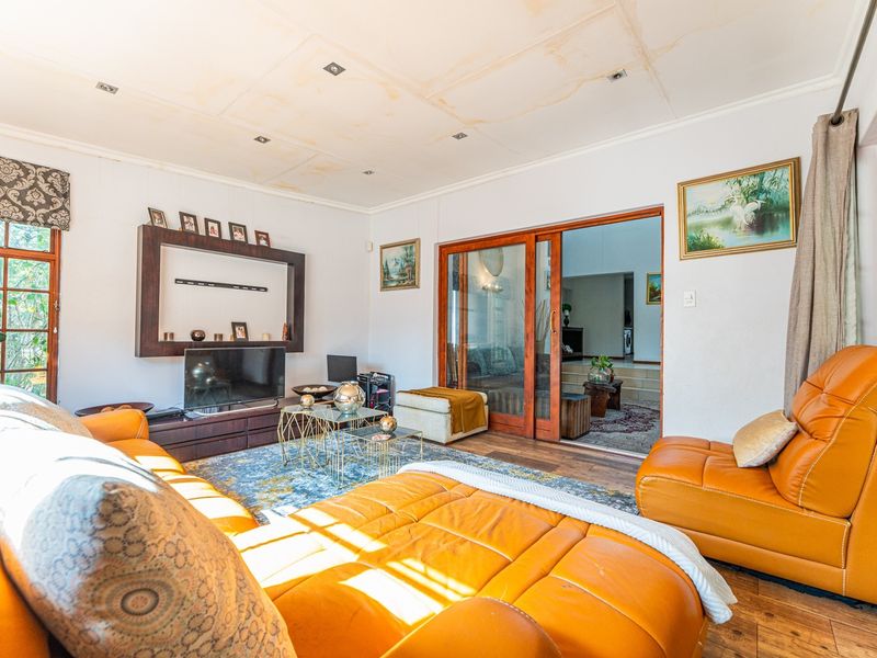 Spacious living room featuring laminate flooring, built-in shelving, and sliding glass doors leading to an adjacent room. Note visible water damage on the ceiling.
