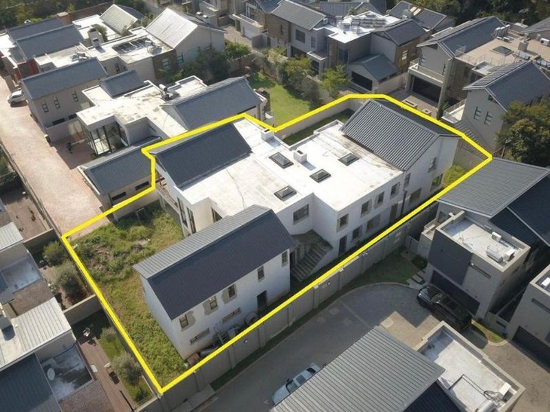 Aerial view of a residential property highlighting the building footprint, metal roofing, skylights, and surrounding garden area within a secure estate.