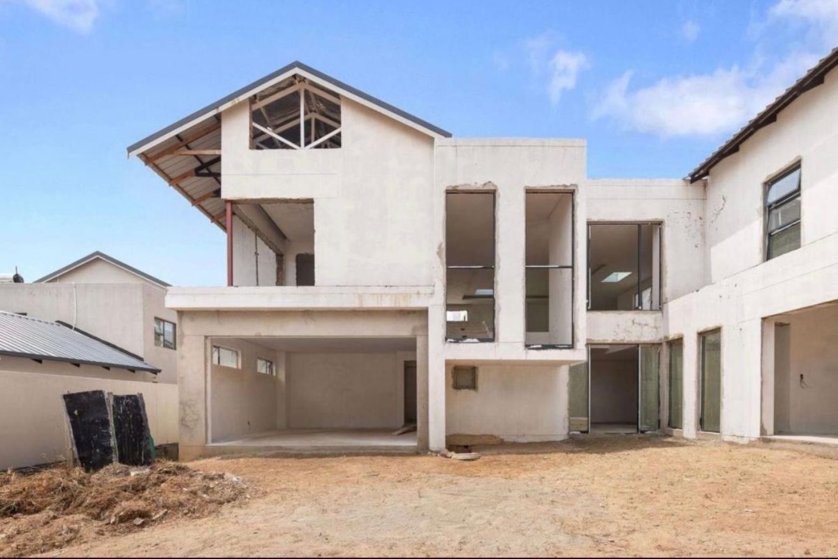 Rear view of a double-storey residential property currently under construction, featuring exposed structural elements and an unfinished exterior facade.