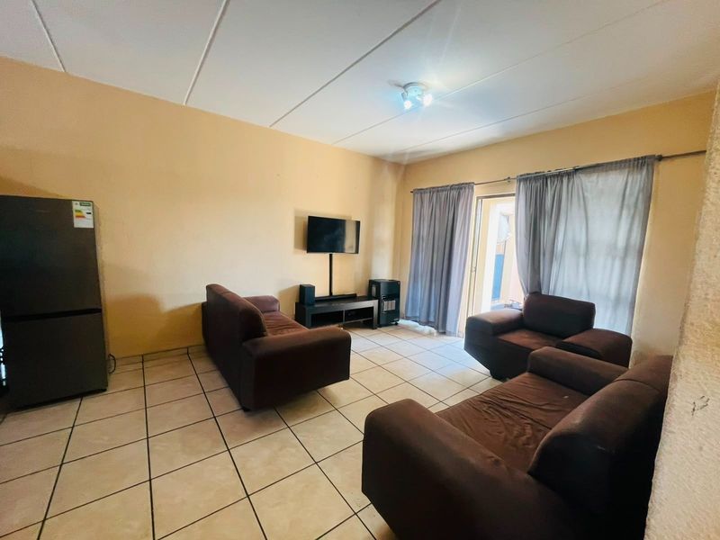 A living room featuring tiled flooring and a sliding door leading to an outdoor area, with neutral wall tones and ceiling paneling.
