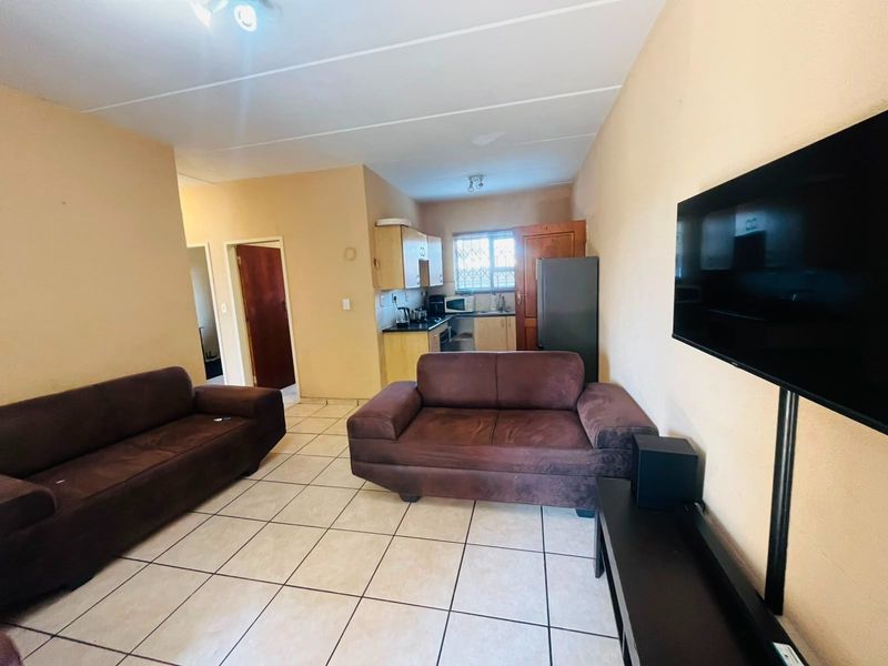 Open-plan living area featuring tiled flooring and a compact kitchen space with built-in cabinetry, providing a functional layout for daily living.