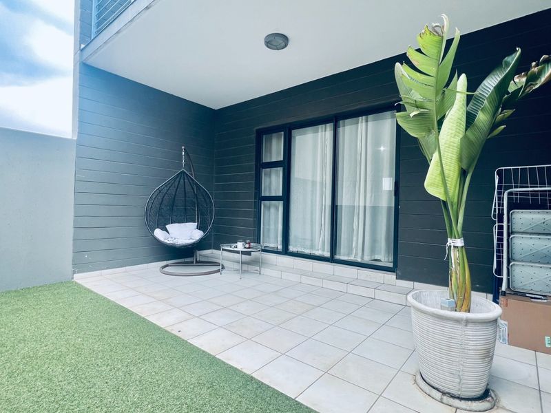 A covered patio area featuring tiled flooring, dark wall cladding, and a large sliding glass door providing access to the interior.