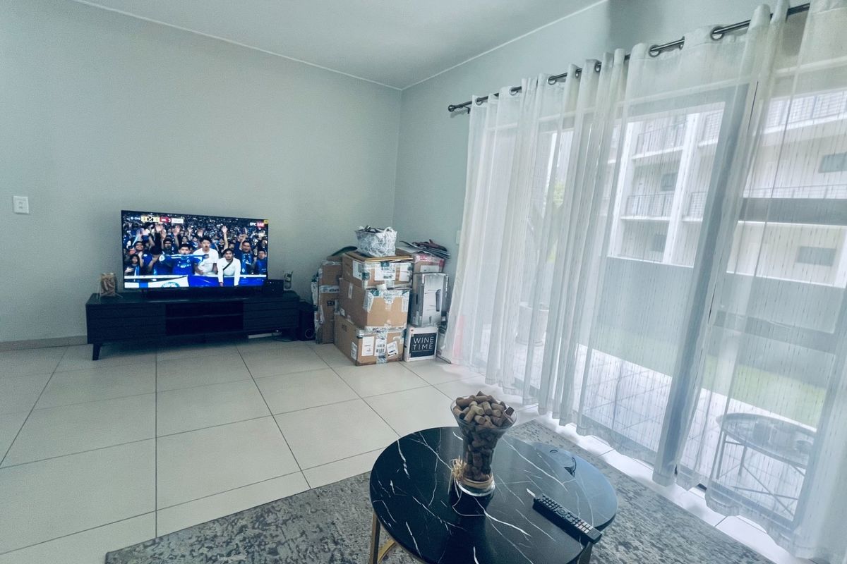 A bright living room featuring large format floor tiles and a sliding glass door providing access to the exterior.