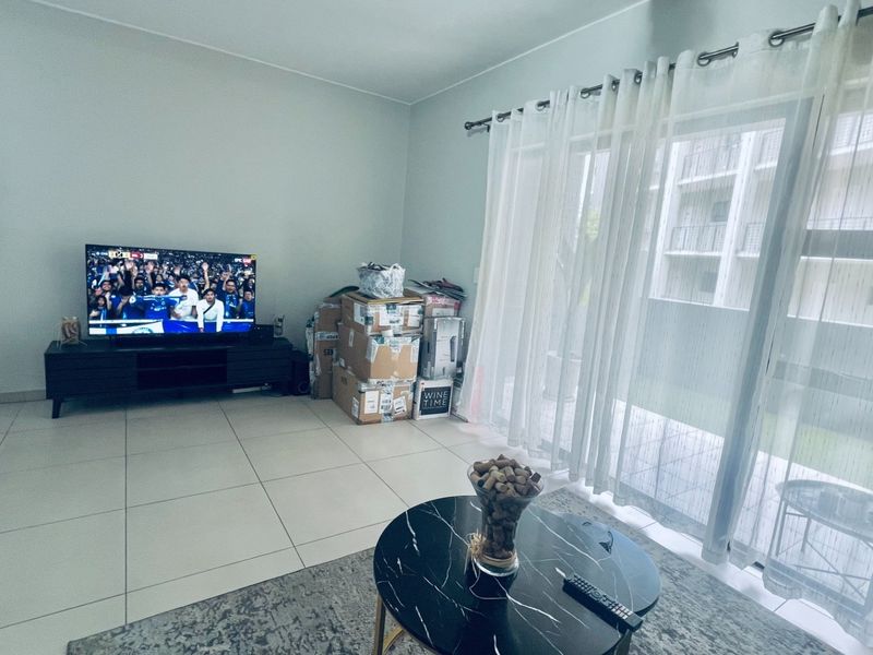 A bright living room featuring large format floor tiles and a sliding glass door providing access to the exterior.