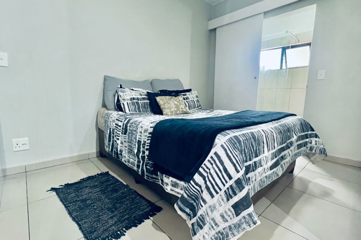A bedroom featuring tiled flooring and a sliding door leading to an adjacent bathroom area.