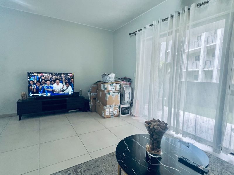 A living room featuring large format floor tiles and a sliding glass door providing access to an outdoor area.