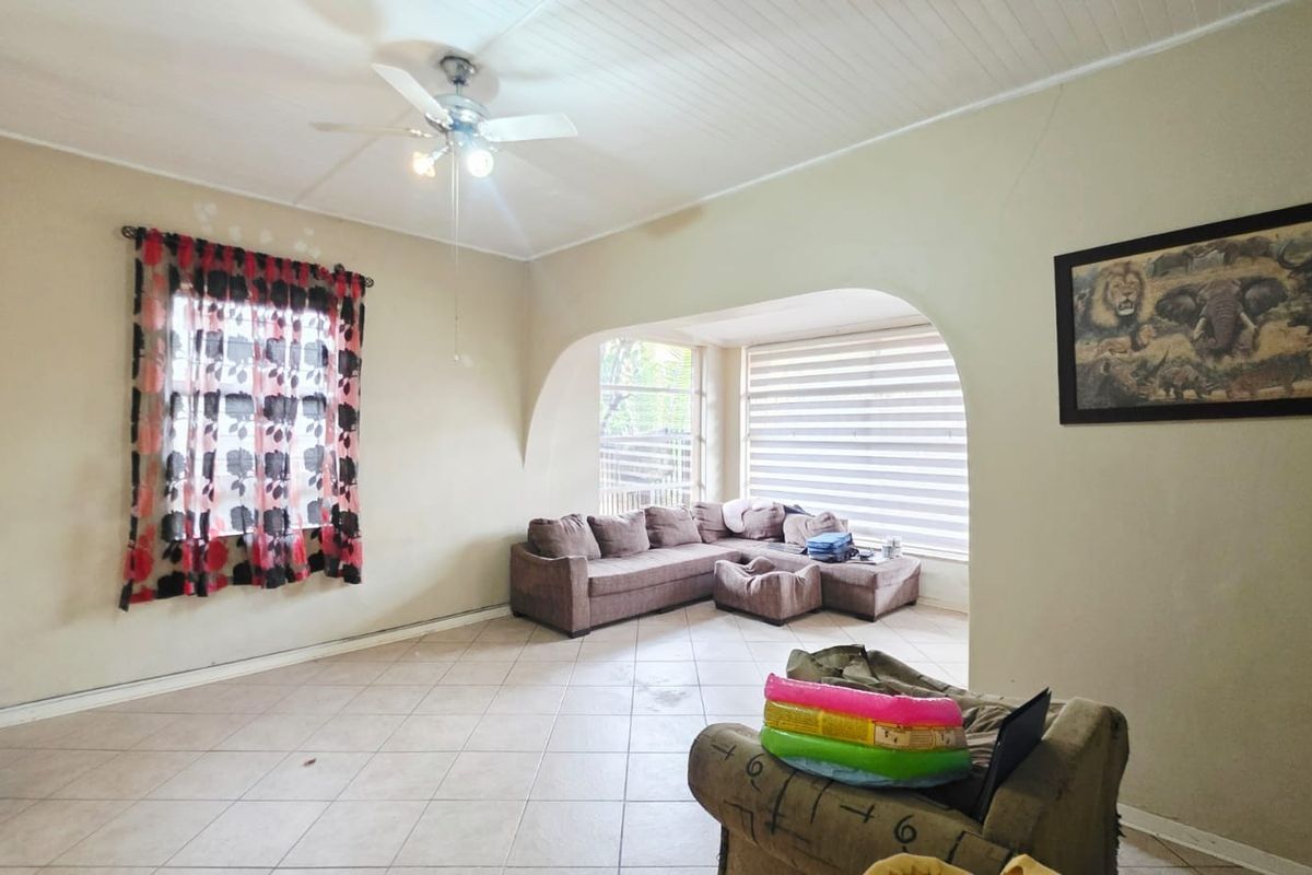 Spacious living room featuring tiled flooring, a ceiling fan, and a distinct arched transition to a sunlit seating area.