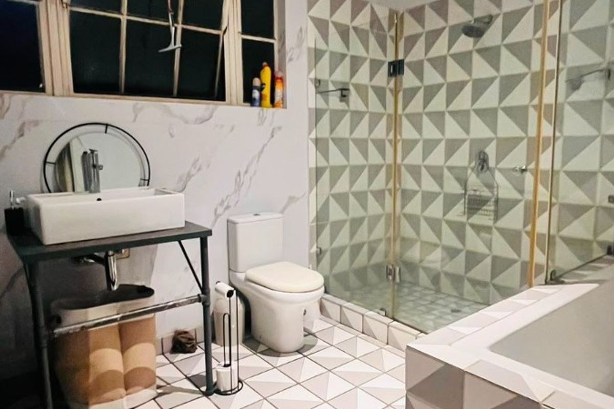 Modern bathroom featuring a vessel sink, glass-enclosed shower, built-in bathtub, and striking geometric tile work on both the floors and shower walls.