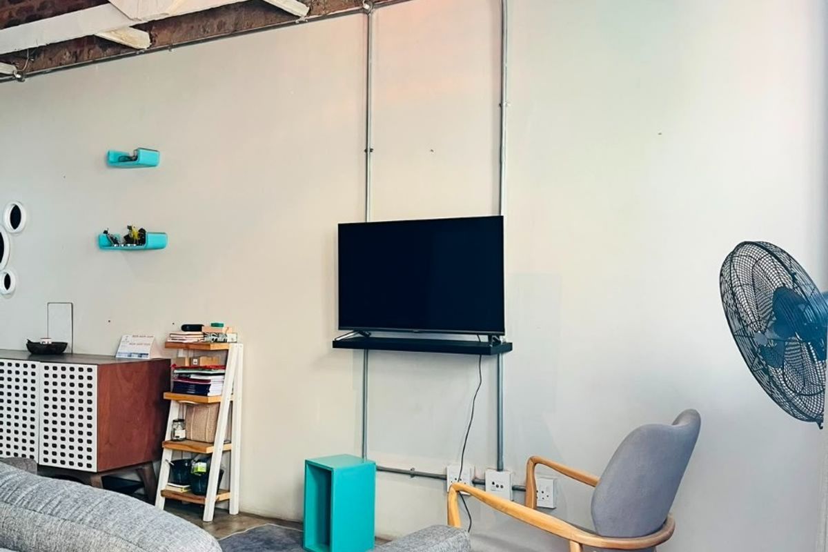 Industrial-style living room featuring exposed brick walls, timber roof trusses, and polished concrete floors with exposed conduit electrical detailing.