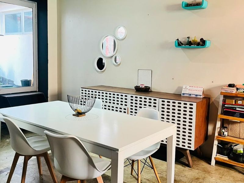 Dining area featuring exposed timber ceiling beams, polished concrete flooring, and natural light from an adjacent window.