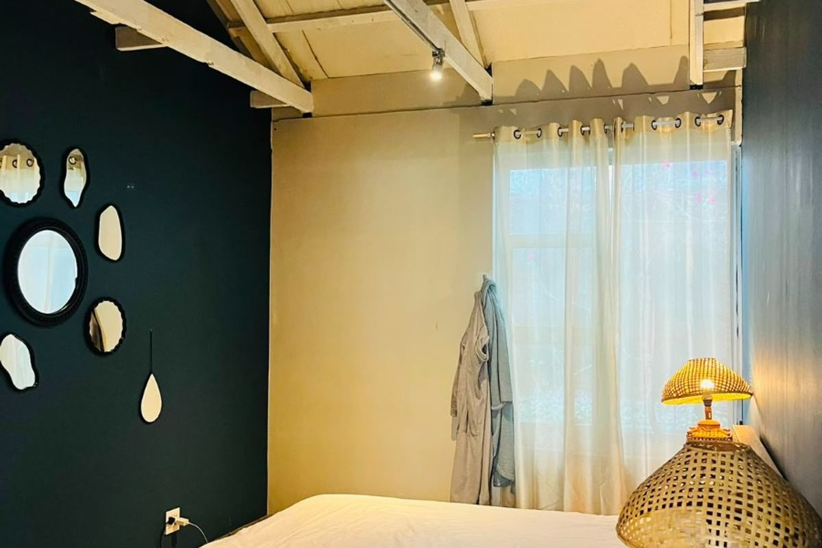 A bedroom featuring high ceilings with exposed timber roof trusses, polished concrete flooring, and modern track lighting.