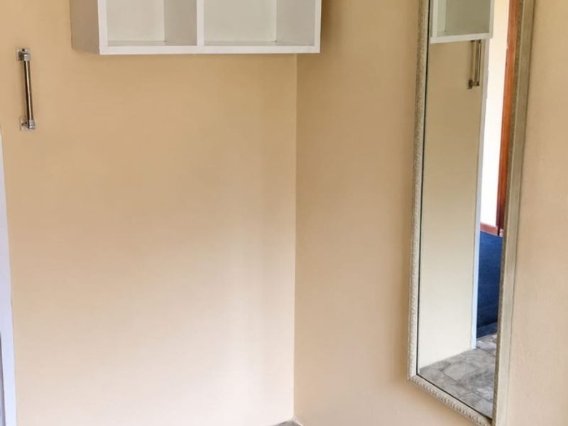 A compact entry area featuring tiled flooring and a wall-mounted storage unit, providing a functional space for coats and accessories.
