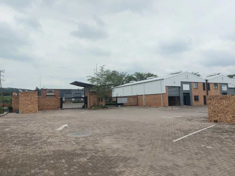 Industrial property exterior featuring a paved driveway, brick facade, and secure roller shutter access points.