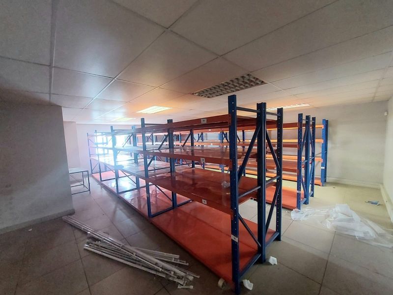 Industrial utility space featuring heavy-duty metal shelving units, suspended ceiling with recessed lighting, and tiled flooring, suitable for storage or warehouse operations.