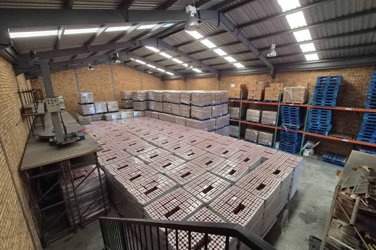 Spacious industrial warehouse featuring exposed steel roof trusses, skylights, face brick walls, and heavy-duty metal racking systems for efficient storage and logistics operations.