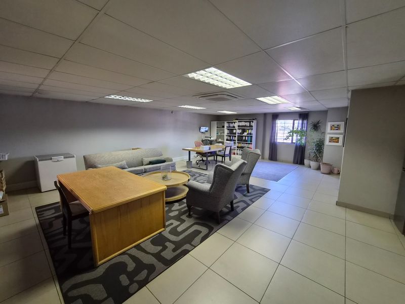Spacious open-plan office area featuring a suspended ceiling with recessed lighting, ceramic tiled flooring, and integrated ducted air conditioning.