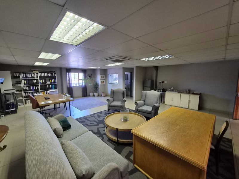Spacious office area featuring suspended ceilings with recessed lighting, tiled flooring, and built-in storage cabinetry, suitable for a professional workspace.
