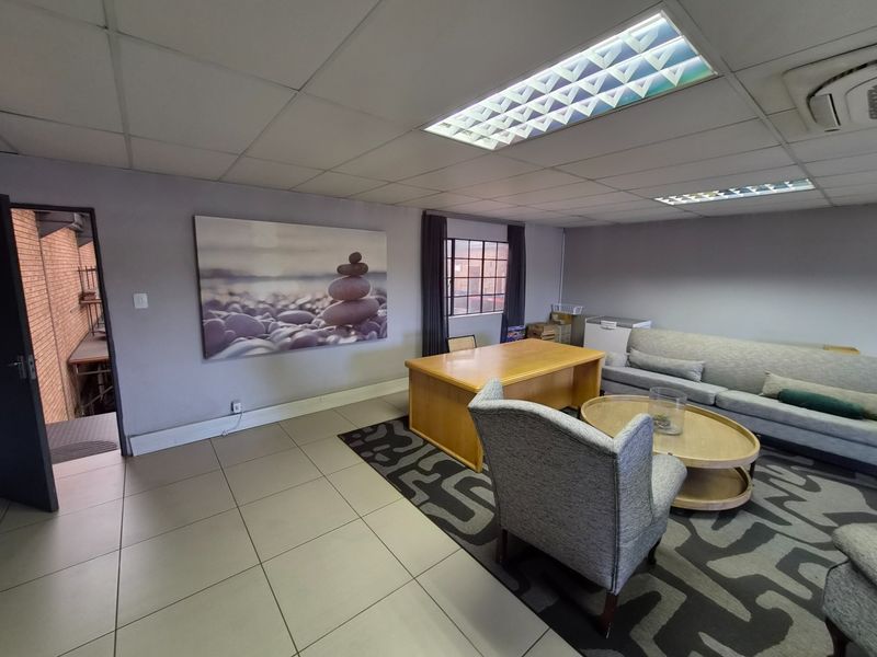 A functional office space featuring ceramic floor tiles, a suspended ceiling with recessed lighting, and integrated air conditioning.