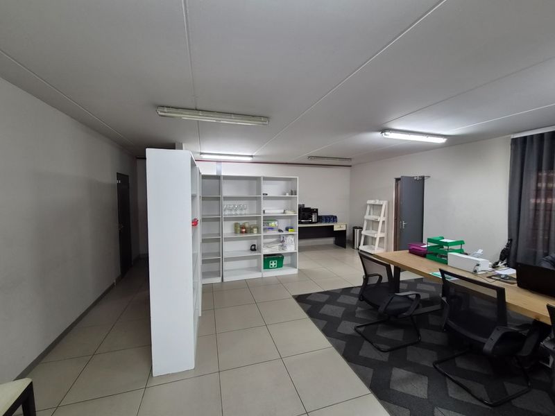 A functional office space featuring tiled flooring, built-in shelving units, and overhead fluorescent lighting, providing a clean and organized work environment.