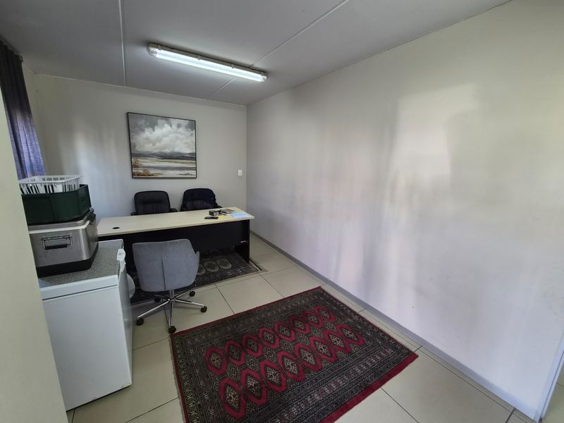 A functional office space featuring tiled flooring and overhead fluorescent lighting, suitable for a professional work environment.