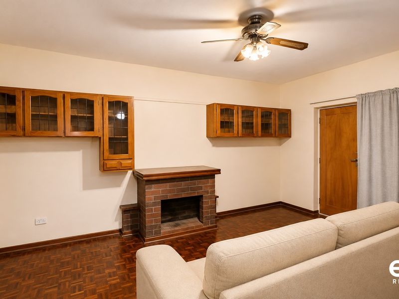 Living room featuring a brick fireplace, built-in wooden wall cabinetry, parquet flooring, and a ceiling fan.