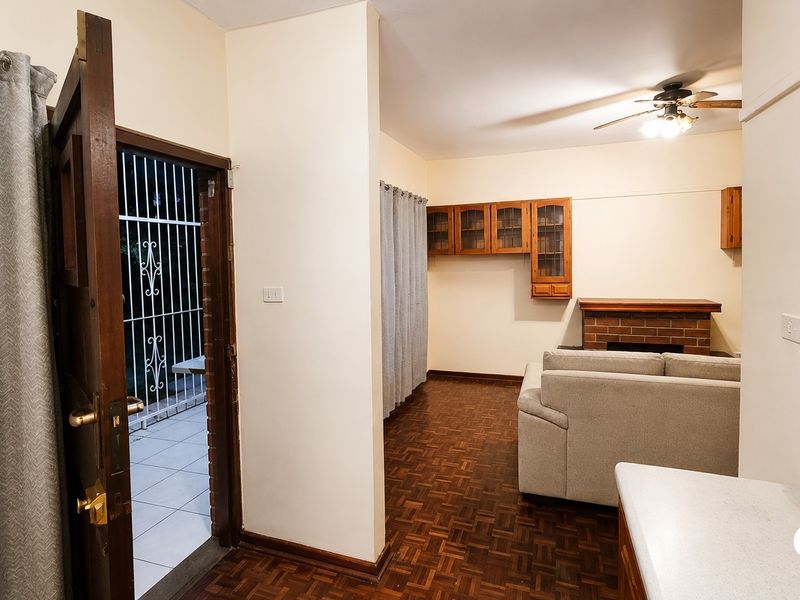 Living room featuring classic parquet flooring, a brick fireplace, and built-in wall cabinetry, with direct access to an exterior patio area.