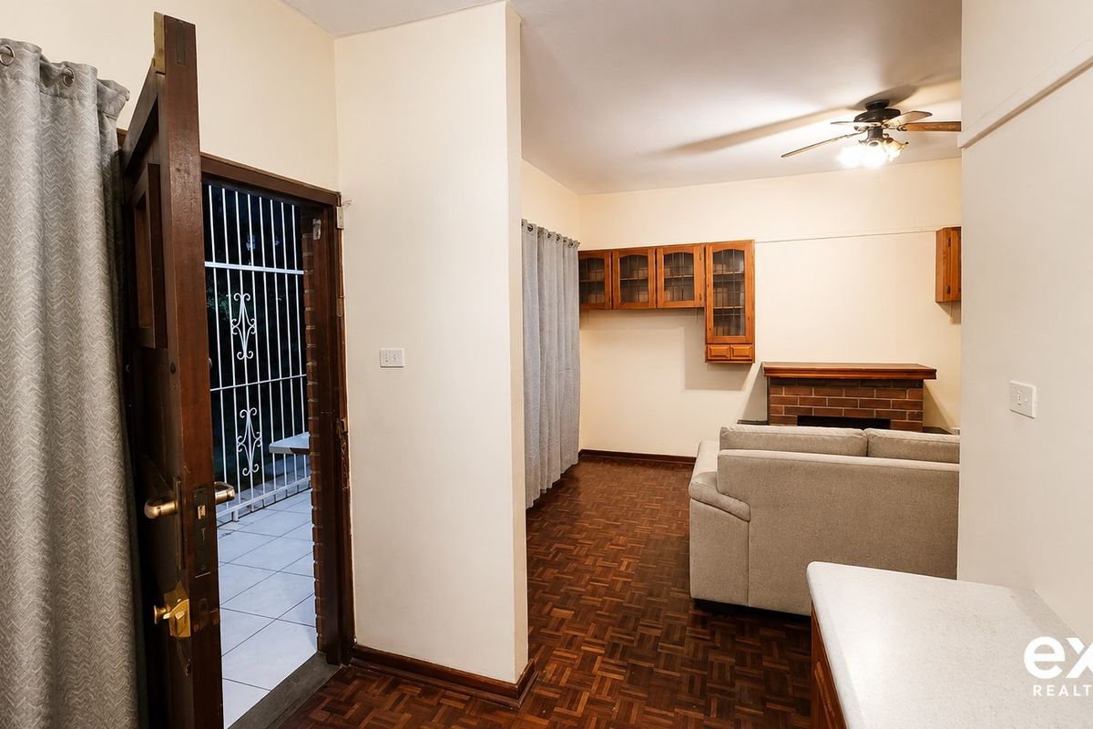 Living room featuring classic parquet flooring, a brick fireplace, and built-in wall cabinetry, with direct access to an exterior patio area.