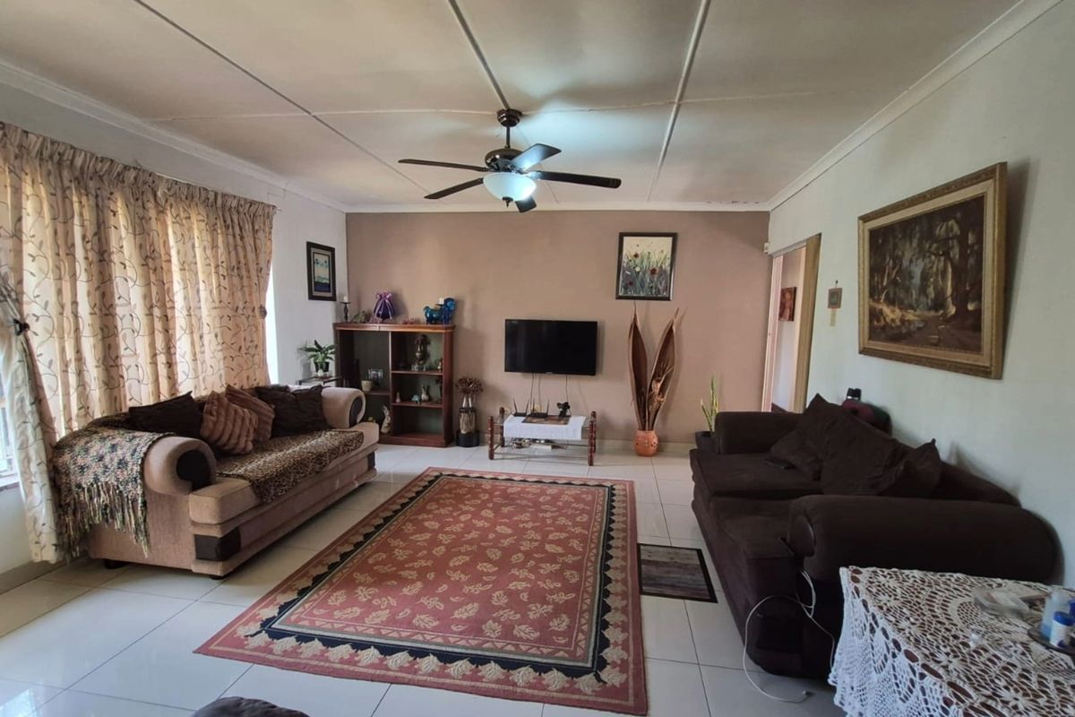 A spacious living room featuring tiled flooring, a ceiling fan, and coved ceilings, offering a comfortable and functional layout for relaxation.