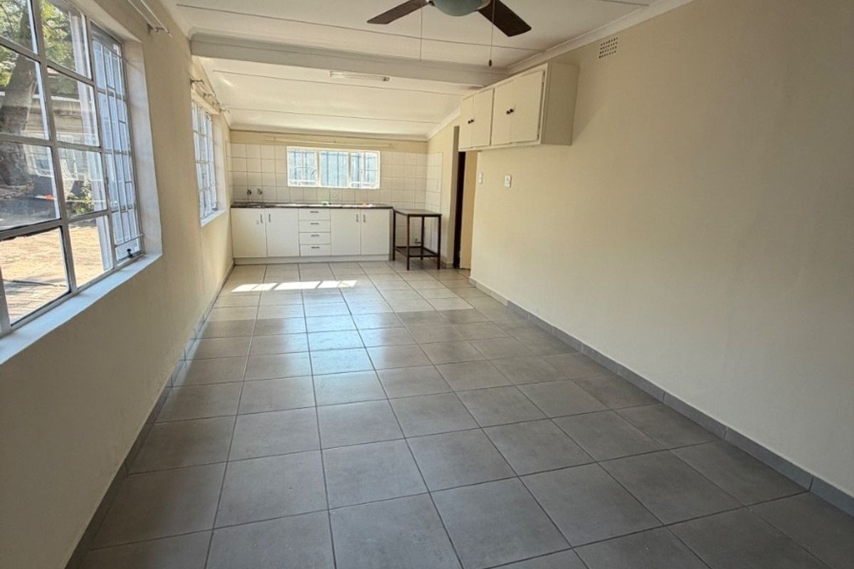 A functional, empty kitchen space featuring tiled flooring, built-in cabinetry, a tiled backsplash, and a ceiling fan.
