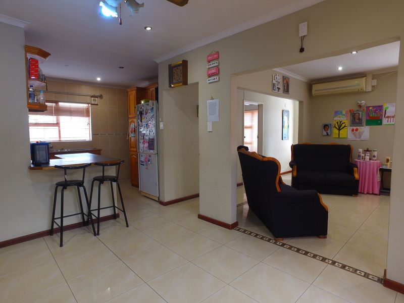 Open-plan living and kitchen area featuring tiled flooring, a breakfast bar, and a wall-mounted air conditioning unit.
