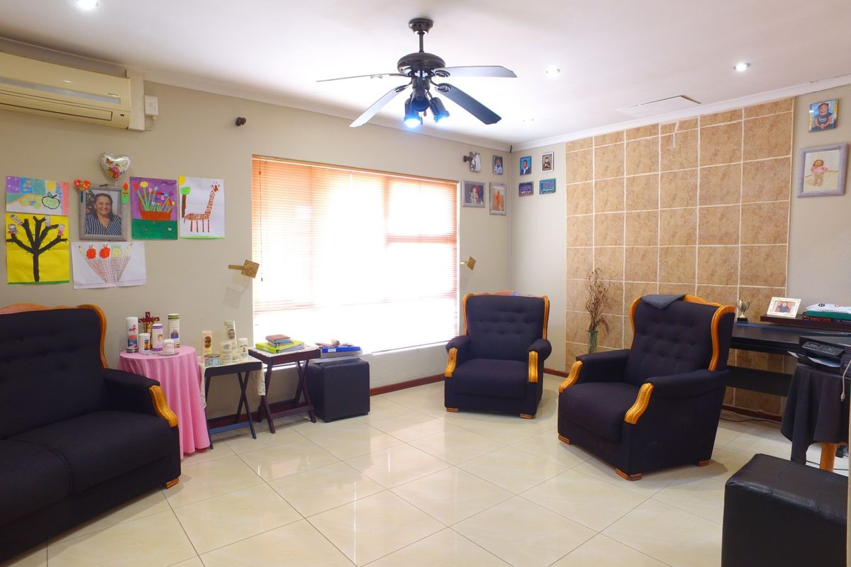 A living room featuring tiled flooring, a ceiling fan, split-system air conditioning, and a decorative tiled feature wall.