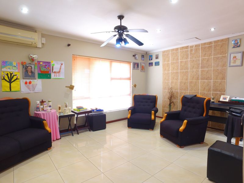 A living room featuring tiled flooring, a ceiling fan, split-system air conditioning, and a decorative tiled feature wall.