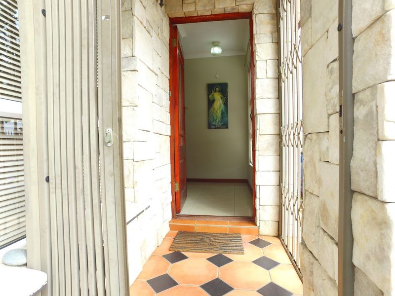 Entrance area featuring stone cladding, security gate, and tiled flooring leading into the home interior.