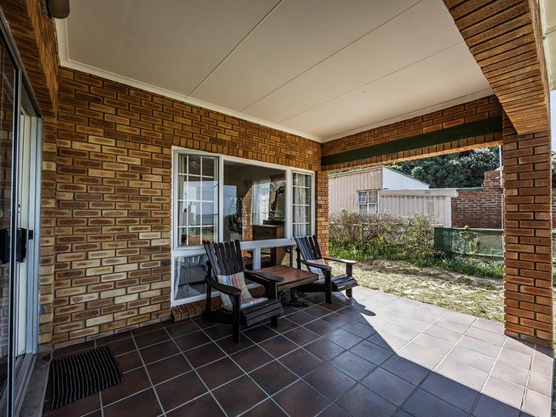 A covered outdoor patio featuring tiled flooring and exposed brick walls, providing a functional space for outdoor relaxation.
