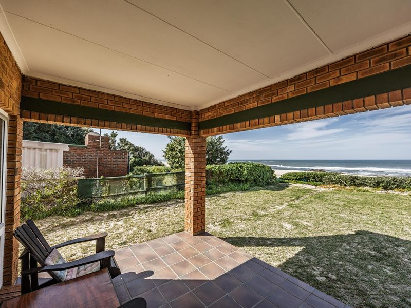 A covered brick patio featuring tiled flooring, offering direct access to the garden and scenic ocean views.