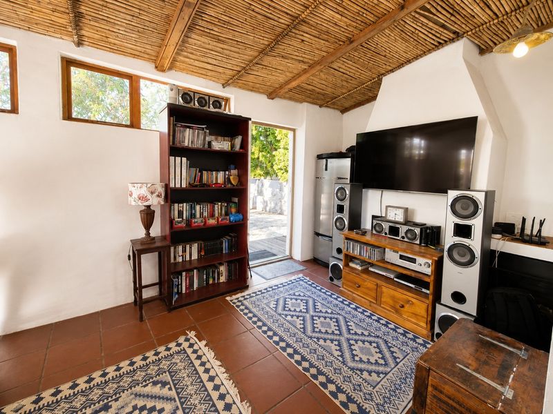 Cozy living room featuring a unique bamboo ceiling, terracotta floor tiles, and a built-in fireplace, with direct access to an outdoor area.