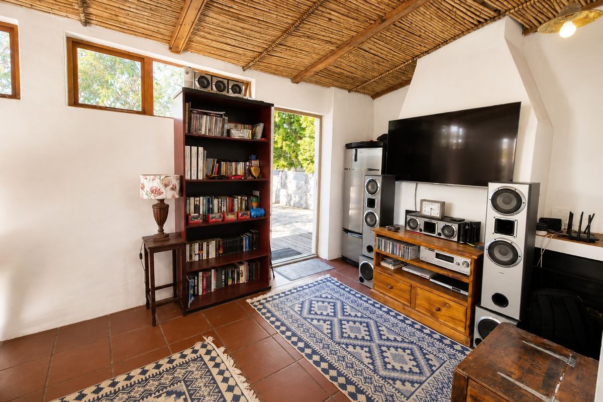 Cozy living room featuring a unique bamboo ceiling, terracotta floor tiles, and a built-in fireplace, with direct access to an outdoor area.