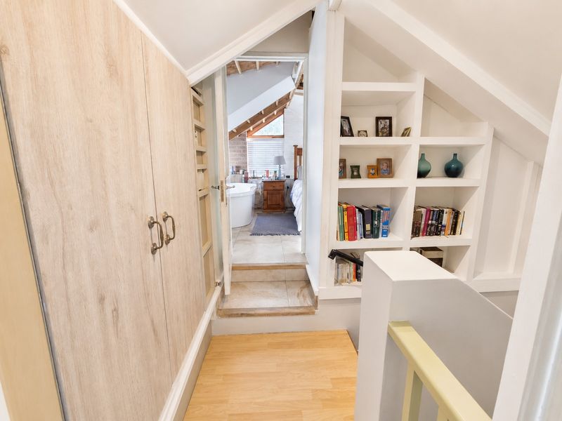 A bright hallway featuring built-in wooden cabinetry and integrated shelving, leading to an adjacent bedroom with an en-suite bathroom.