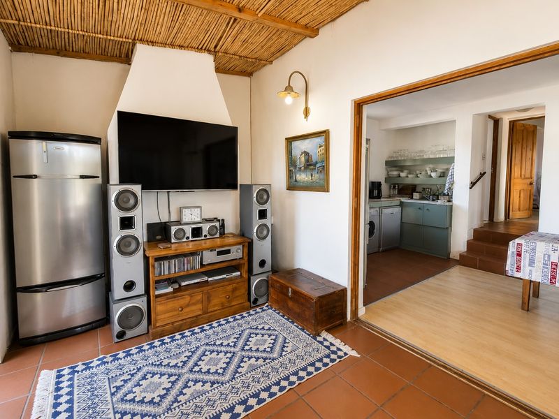 A living area featuring a unique exposed reed ceiling, tiled floors, and a fireplace chimney breast, with an adjacent view into the kitchen area.