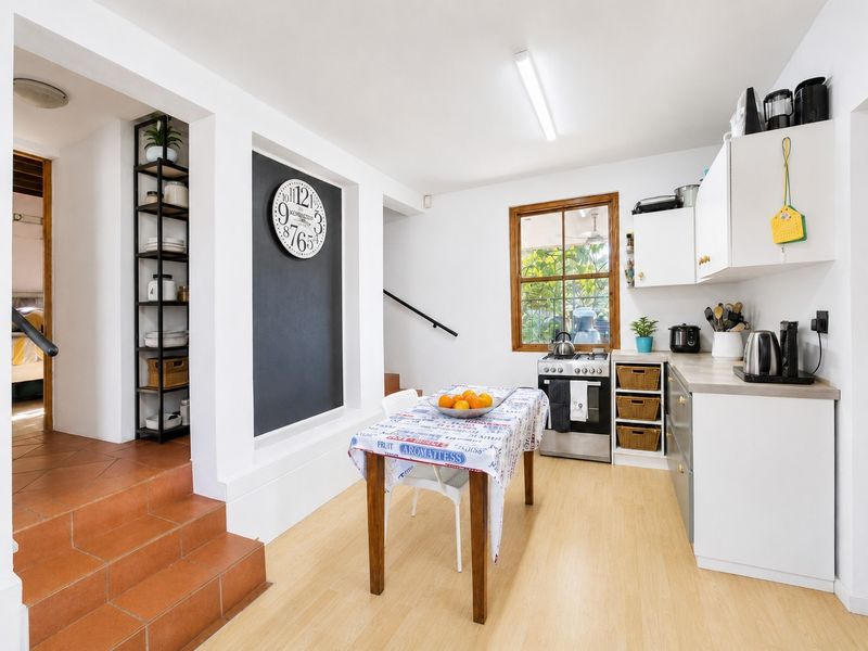 A functional kitchen featuring built-in cabinetry, a gas stove, and oven, with tiled steps leading to an adjacent living area.